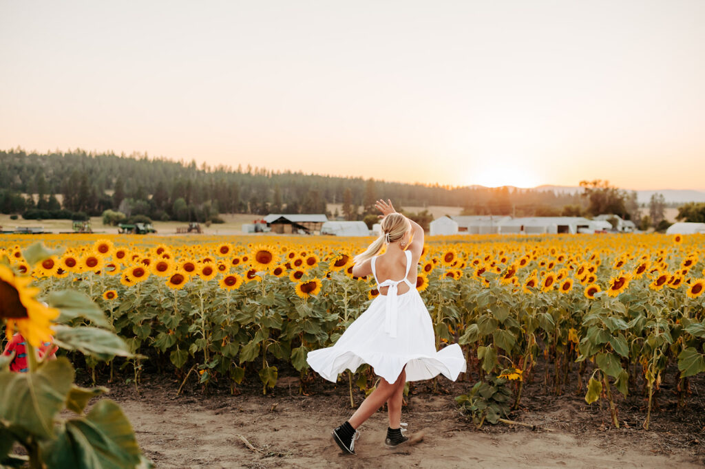 Little girl spinning at Half Moon Blooms in the sunflower field during golden hour
